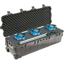 A large, elongated black Pelican 1740 Protector Case shown open and lying flat. The case is customized with a foam insert holding three blue ARRI film lights and a collapsed silver light stand. The lid features thick egg-crate foam for protection.